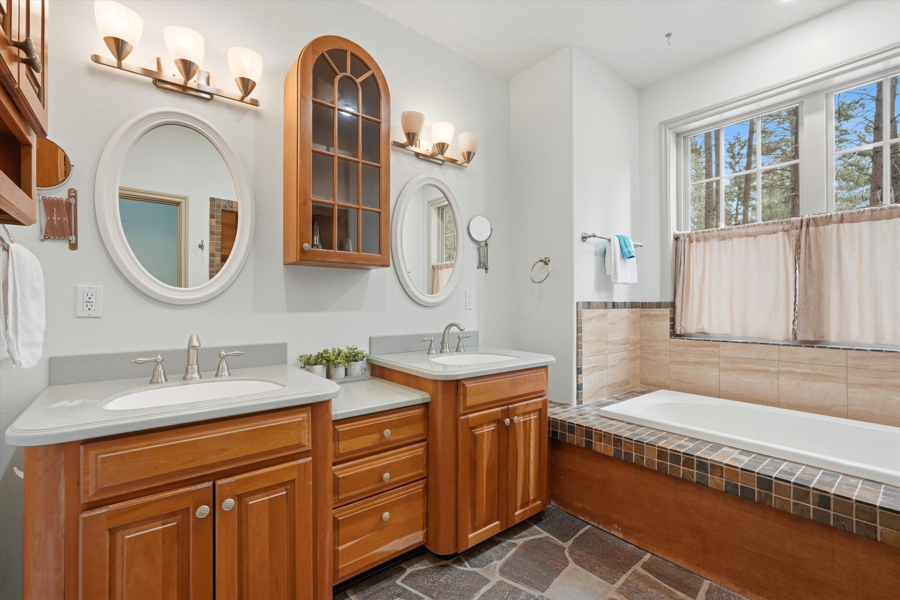 17179 Island Loop Way Bend, OR 97707 - Photo 25 of 52 a spacious bathroom with a granite countertop tub sink and mirror