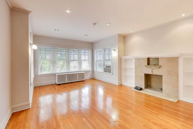 a view of empty room with wooden floor and fireplace