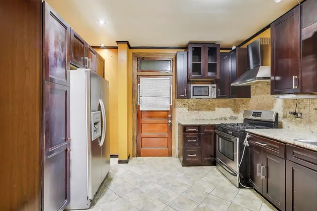 a kitchen with stainless steel appliances granite countertop a refrigerator and a stove top oven