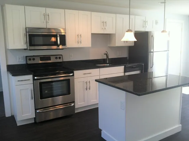 a kitchen with granite countertop a stove and a microwave with cabinets