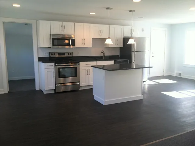 a kitchen with kitchen island a sink appliances and cabinets