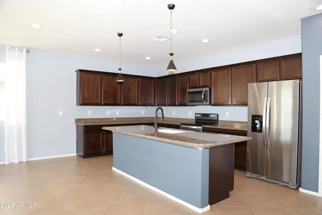 a kitchen with stainless steel appliances granite countertop a refrigerator a sink a stove and a refrigerator with wooden floor