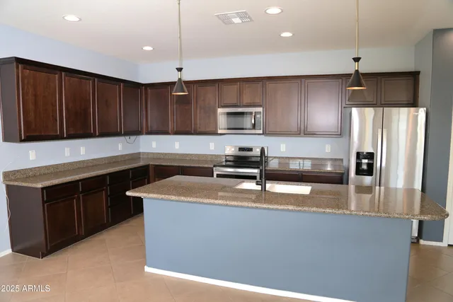 a kitchen with stainless steel appliances granite countertop a sink a stove a refrigerator and a microwave oven