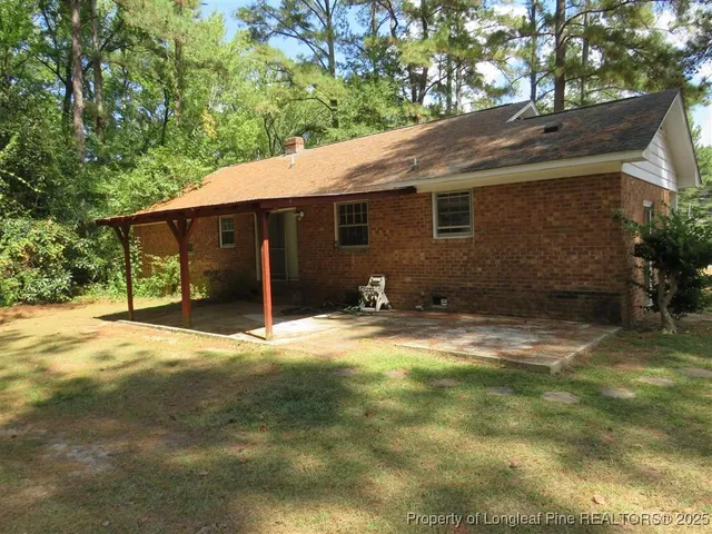 a backyard of a house with table and chairs under an umbrella