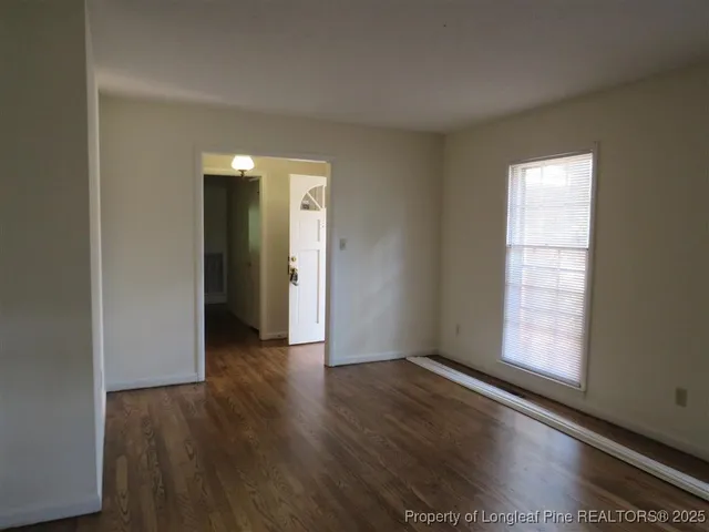a view of an empty room with wooden floor and a window