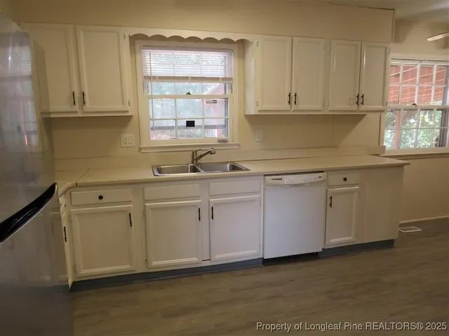 a kitchen with white cabinets white appliances and a sink