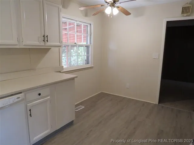 an empty room with wooden floor and fan