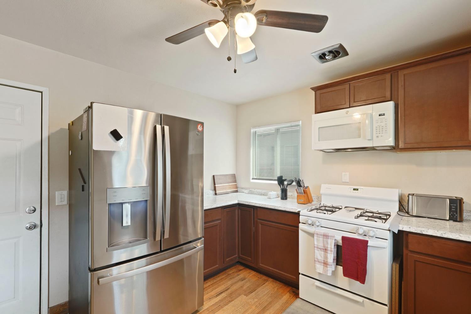 152 Drake Avenue Modesto, CA 95350 - Photo 11 of 52 a kitchen with stainless steel appliances a refrigerator a sink dishwasher a stove and white cabinets with wooden floor