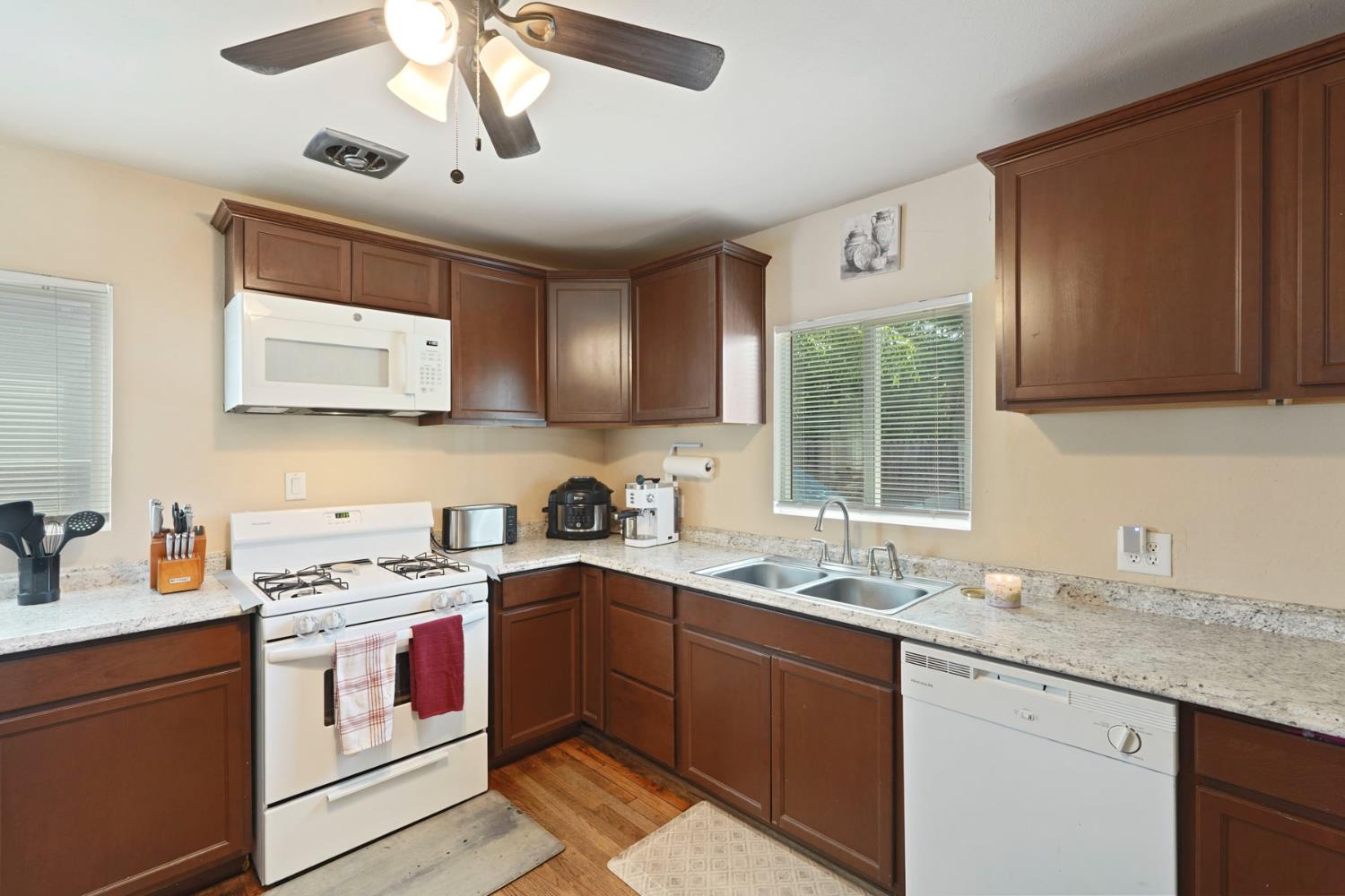152 Drake Avenue Modesto, CA 95350 - Photo 8 of 52 a kitchen with stainless steel appliances granite countertop a sink stove a refrigerator and cabinets with wooden floor