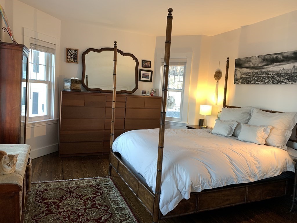 93 Waldeck Road Milton, MA 02186 - Photo 13 of 30 a bedroom with a bed a mirror on dresser and a chandelier