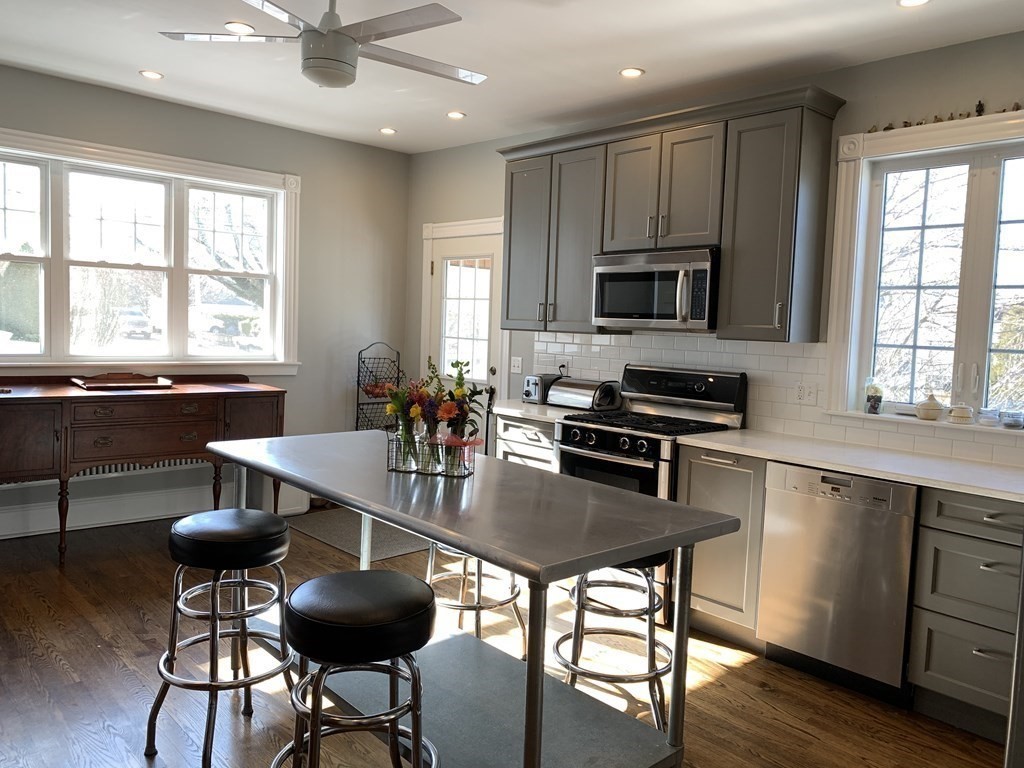 93 Waldeck Road Milton, MA 02186 - Photo 3 of 30 a kitchen with stainless steel appliances granite countertop a stove top oven a sink a dining table and chairs