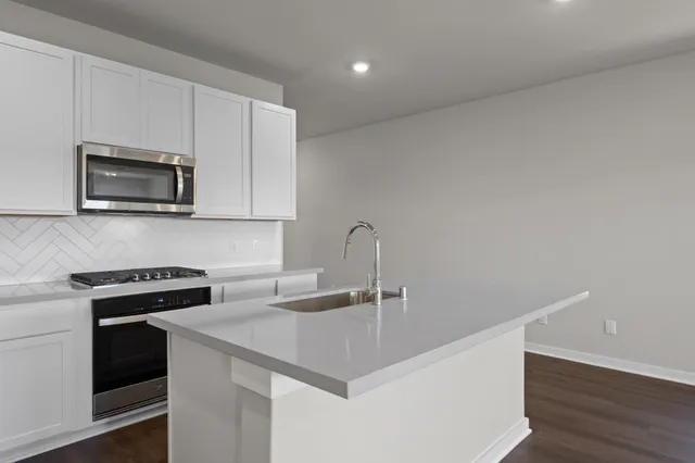 a kitchen with stainless steel appliances a sink a stove a microwave and cabinets
