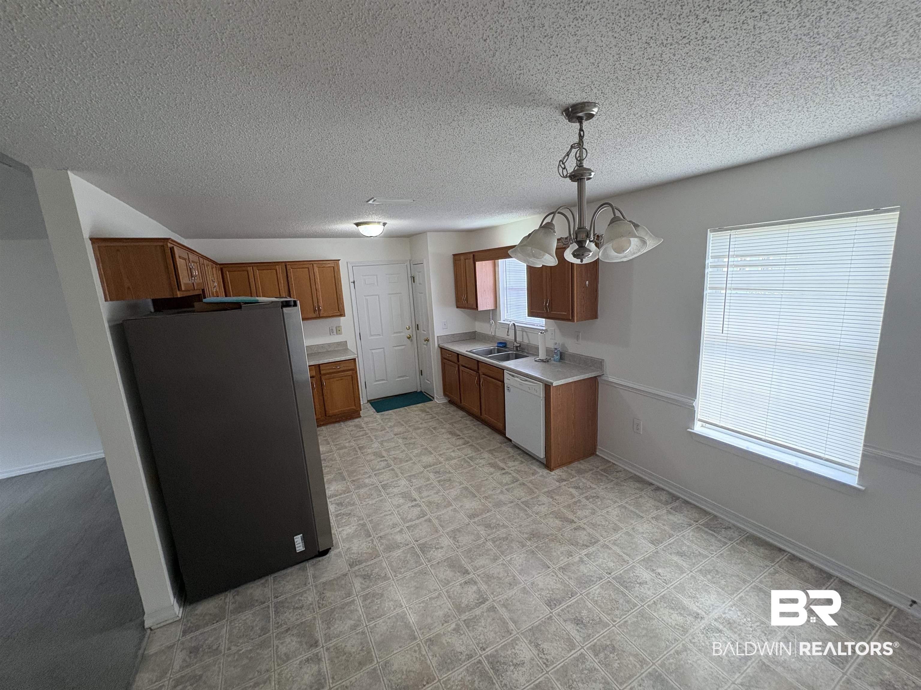 13281 Labradors Run Foley, AL 36535 - Photo 4 of 7 Kitchen featuring brown cabinetry, light countertops, freestanding refrigerator, pendant lighting, and a textured ceiling