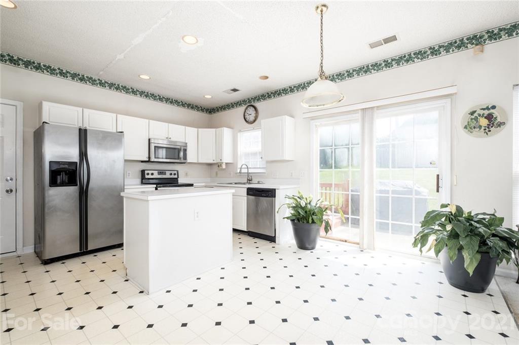 2331 Pimpernel Road Charlotte, NC 28213 - Photo 3 of 30 a kitchen with stainless steel appliances kitchen island granite countertop a refrigerator a sink a stove and white cabinets