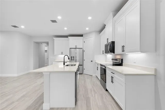 a large kitchen with stainless steel appliances lots of counter space and a sink