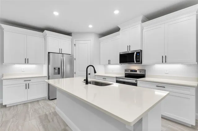 a kitchen with a sink a stove and white cabinets