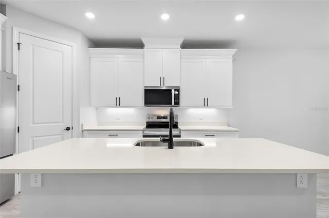 a room with kitchen island white cabinets and stainless steel appliances