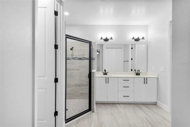 a bathroom with a double vanity sink a mirror and shower