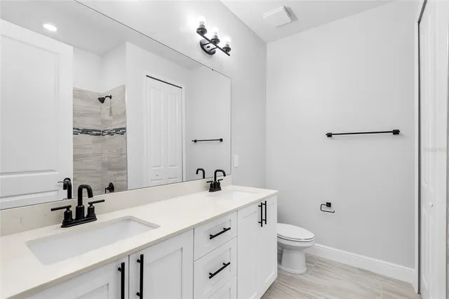 a bathroom with a double vanity sink toilet and mirror