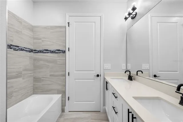 a bathroom with a double vanity sink a mirror and a bathtub