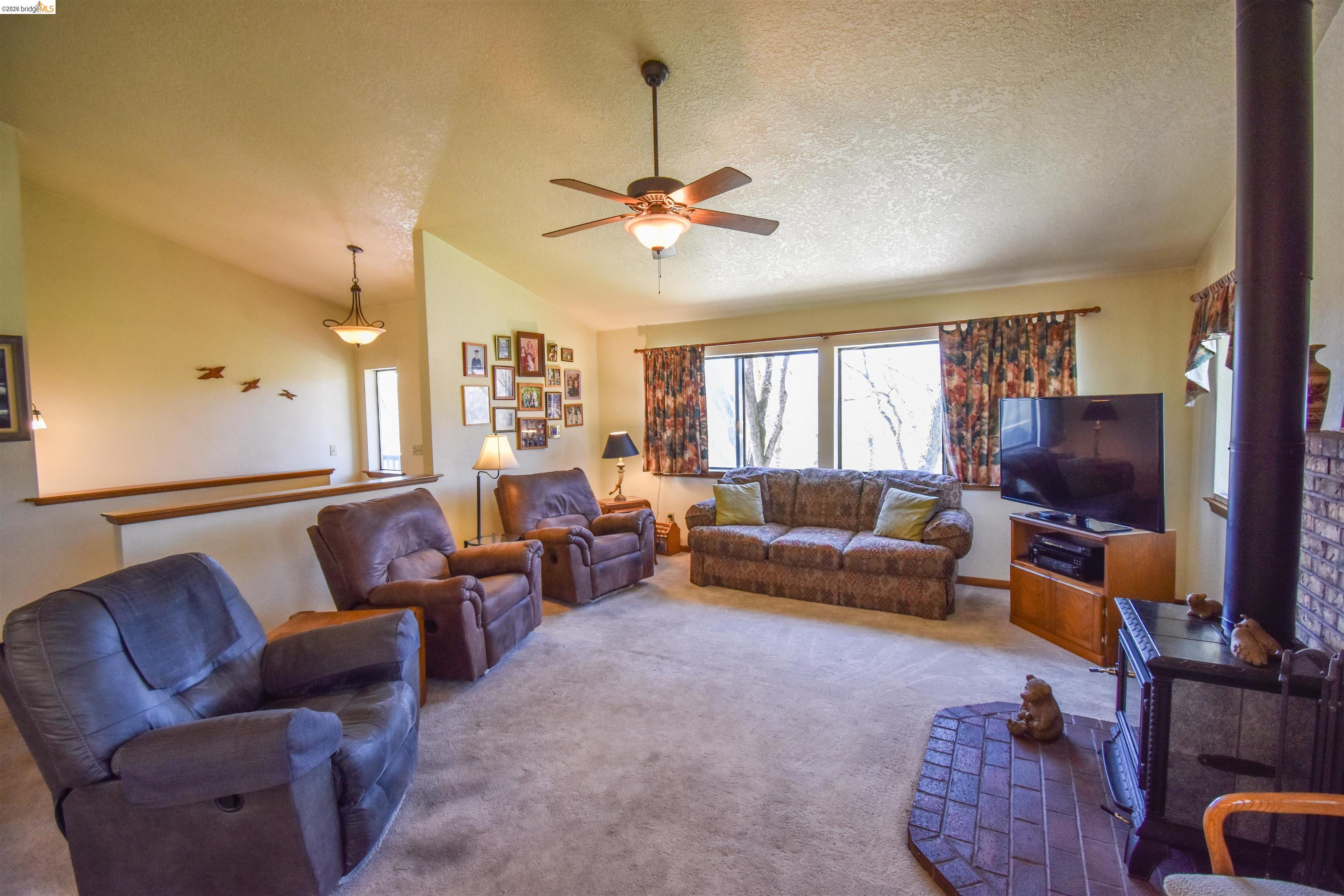 15170 Potato Ranch Road Sonora, CA 95370 - Photo 10 of 49 Carpeted living area featuring a ceiling fan and a wood stove
