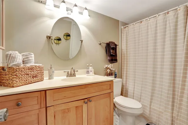 a bathroom with a sink a mirror a toilet and a window