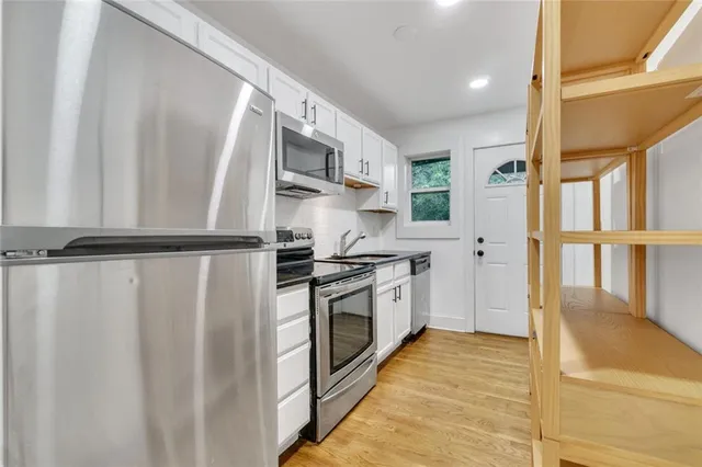 a kitchen with stainless steel appliances granite countertop a refrigerator a sink dishwasher a stove and a microwave oven