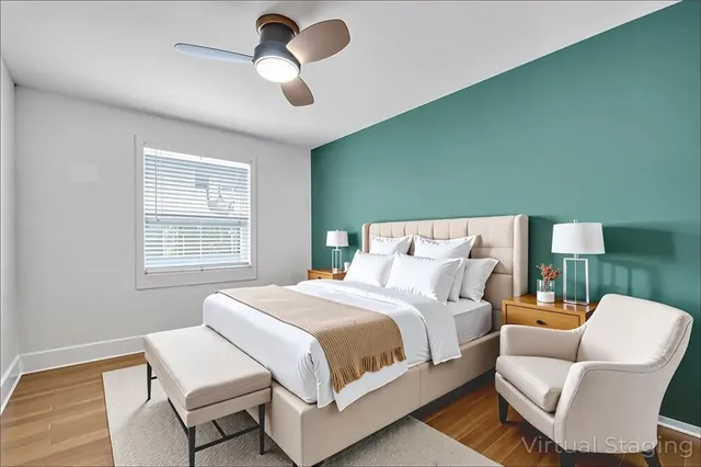 a bedroom with a bed chairs and fan