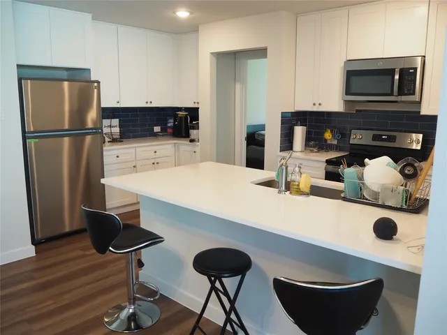 a kitchen with stainless steel appliances granite countertop a refrigerator a stove a sink a dining table and chairs