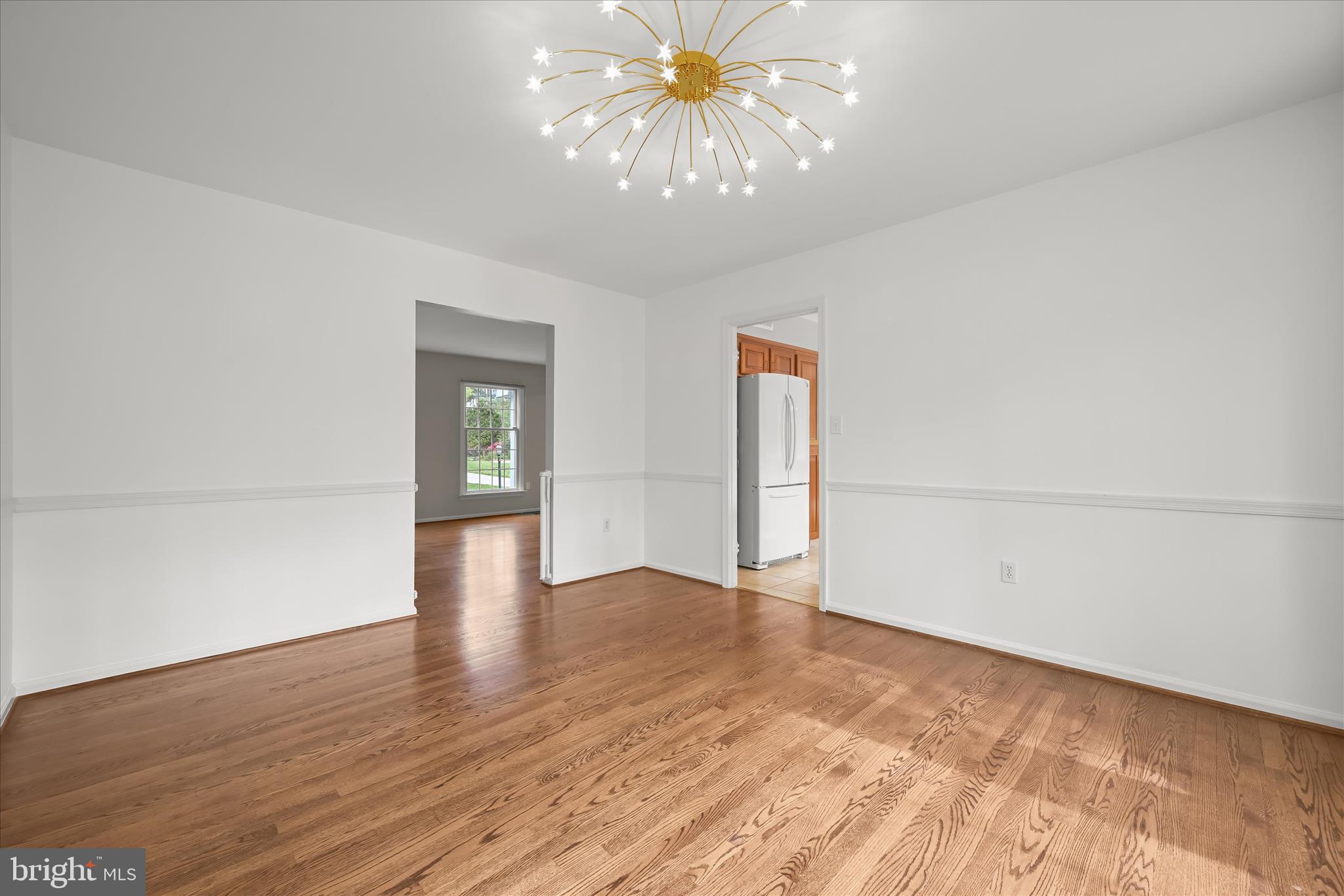 10428 Schoolmaster Place Columbia, MD 21044 - Photo 17 of 69 a view of an empty room with chandelier fan and wooden floor