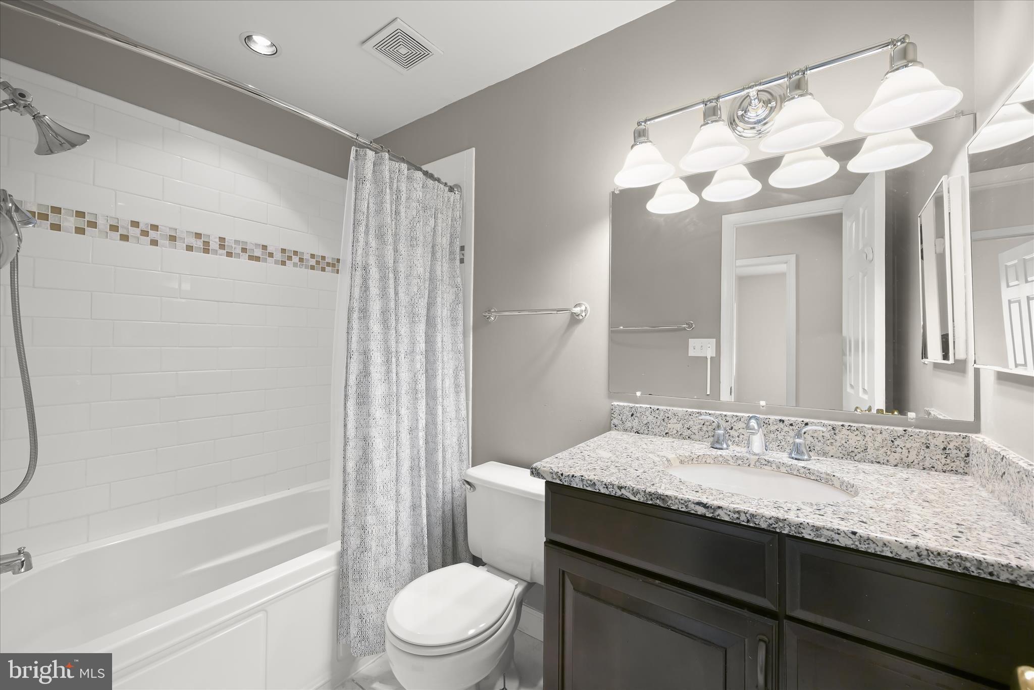 10428 Schoolmaster Place Columbia, MD 21044 - Photo 40 of 69 a bathroom with a granite countertop sink toilet mirror and a bathtub