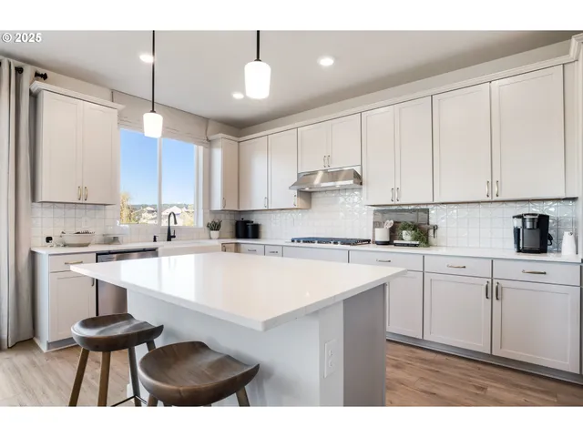 a kitchen with stainless steel appliances kitchen island granite countertop a table chairs and a refrigerator