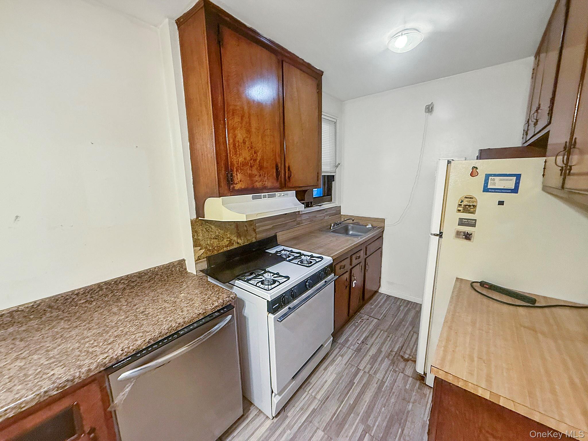 1111 Midland Avenue, Unit 5J Bronxville, NY 10708 - Photo 4 of 13 Kitchen with white appliances, brown cabinets, under cabinet range hood, and light wood finished floors
