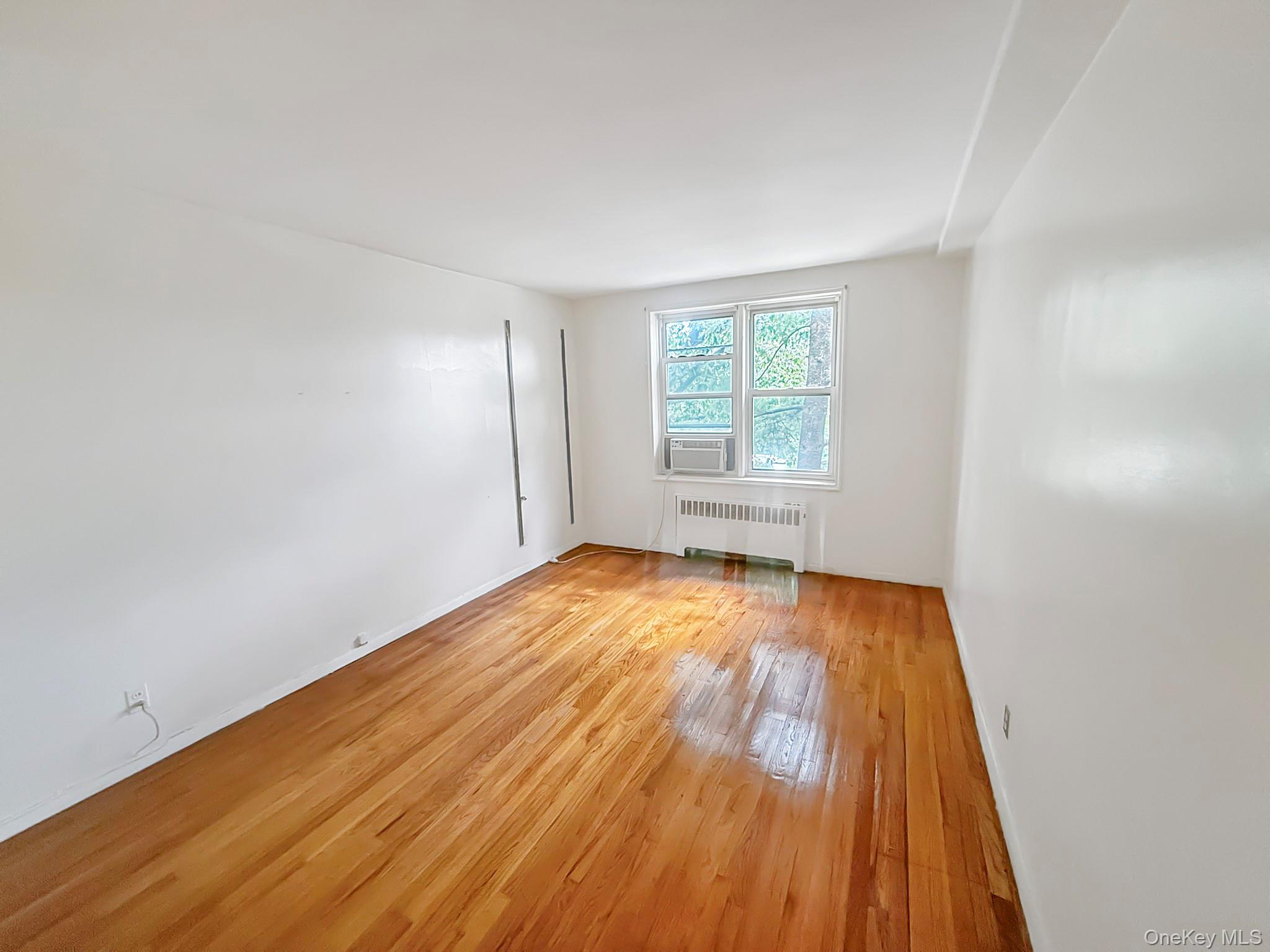 1111 Midland Avenue, Unit 5J Bronxville, NY 10708 - Photo 6 of 13 Empty room with light wood-style floors and radiator heating unit