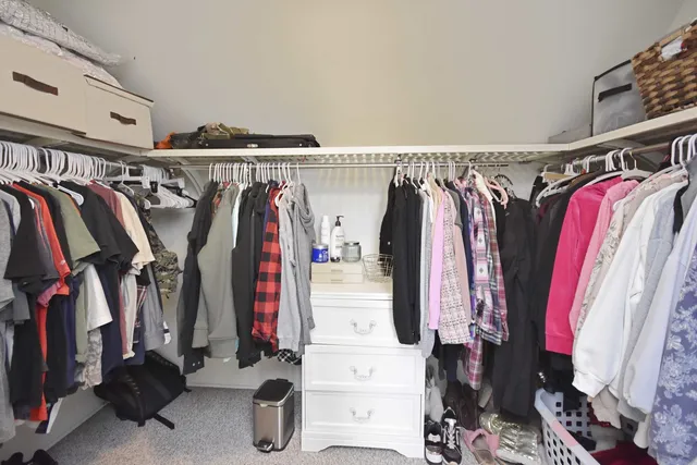 a view of walk in closet with clothes and shoes