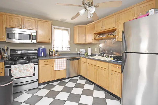 a kitchen with stainless steel appliances granite countertop a refrigerator a sink a stove a microwave and island with wooden floor