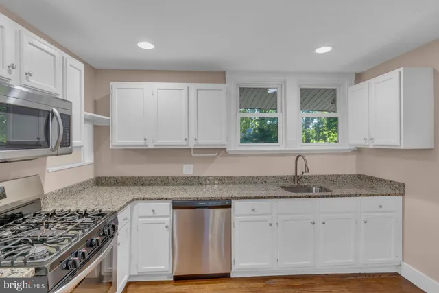 a kitchen with granite countertop stainless steel appliances a stove sink and microwave