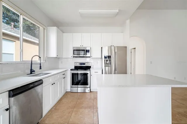 a kitchen with kitchen island a sink appliances and cabinets