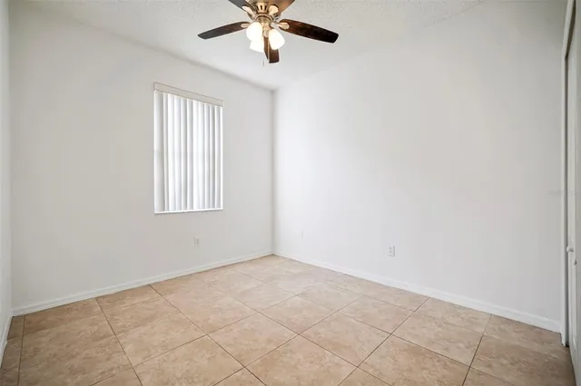 an empty room with chandelier fan and windows