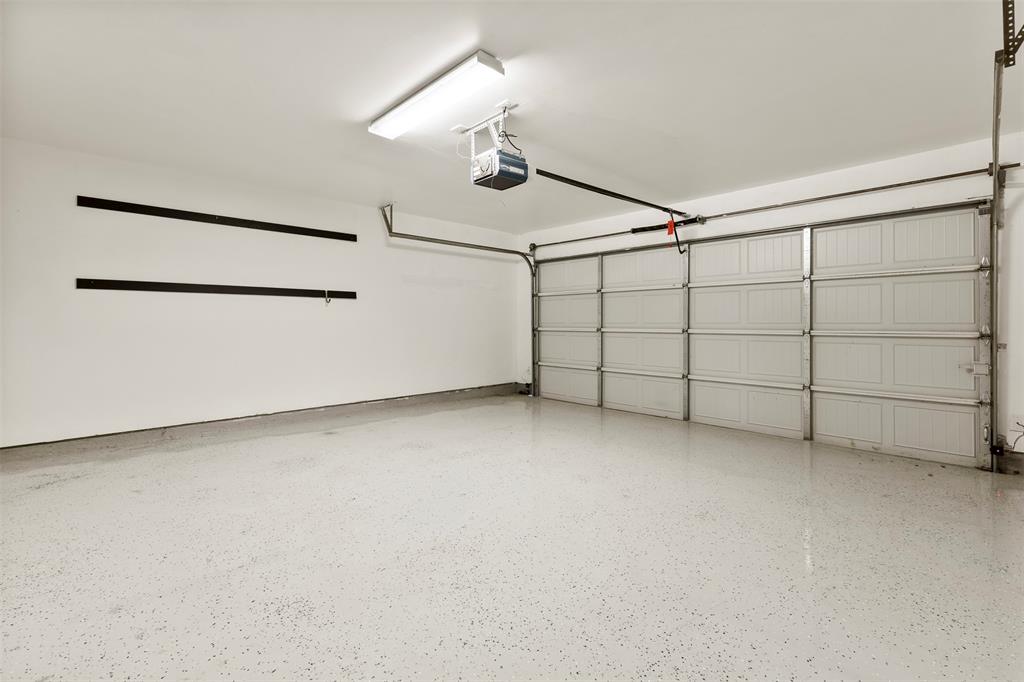 6522 Portside Ridge Lane Dallas, TX 75249 - Photo 27 of 37 Spacious garage featuring a durable speckled epoxy floor, white paneled garage door, and ample wall space