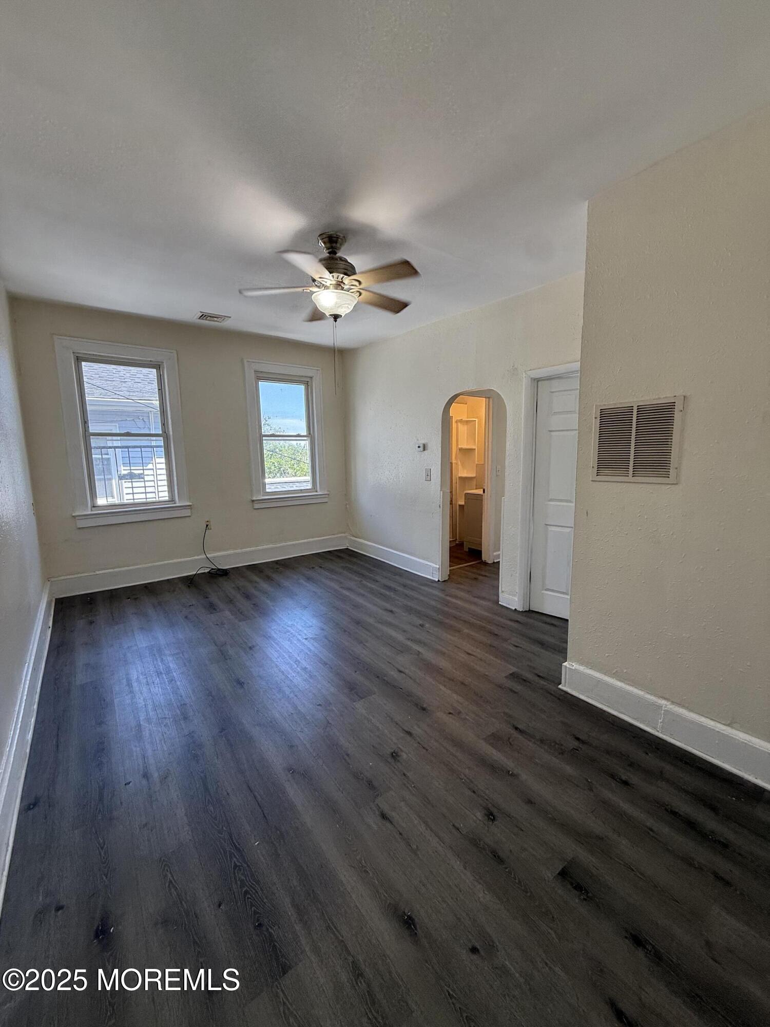 a view of an empty room with wooden floor and window