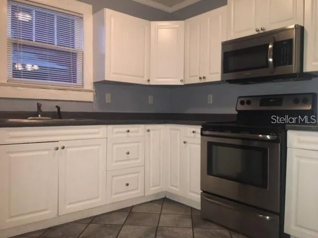 a kitchen with granite countertop white cabinets stainless steel appliances and a sink