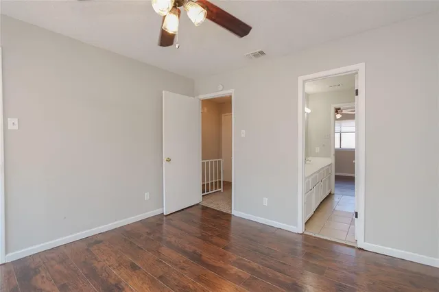 an empty room with wooden floor and ceiling fan