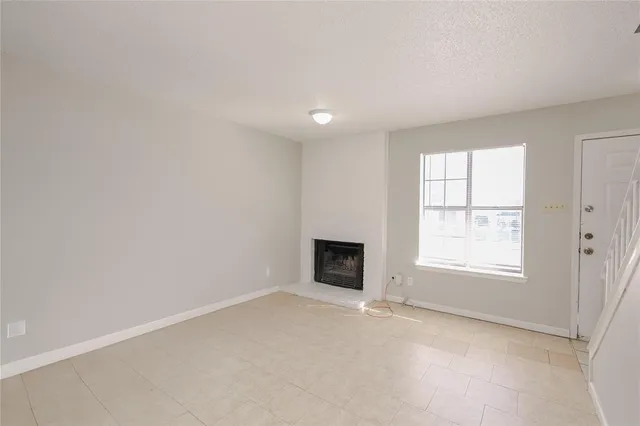 an empty room with a fireplace and windows