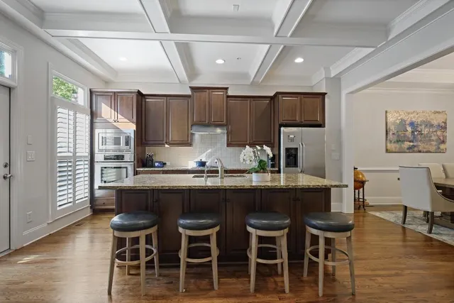 a kitchen with kitchen island granite countertop a dining table chairs cabinets and stainless steel appliances