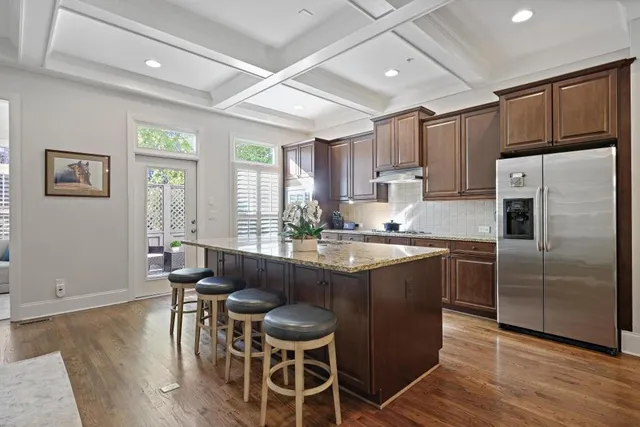 a kitchen with stainless steel appliances granite countertop a stove a refrigerator a sink a dining table and chairs with wooden floor