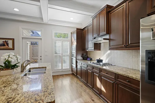 a kitchen with stainless steel appliances granite countertop a stove top oven a sink dishwasher a refrigerator and cabinets with wooden floor