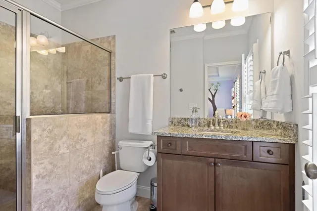 a bathroom with a granite countertop sink toilet a mirror and a shower
