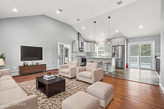 a kitchen with stainless steel appliances granite countertop a refrigerator a stove and a wooden floors