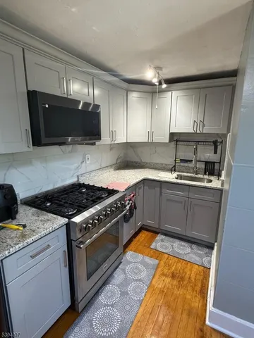 a kitchen with granite countertop a sink a stove and cabinets